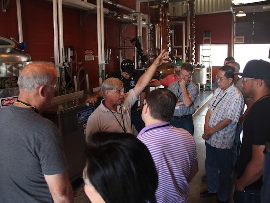 Instrutor conduzindo treinamento prático em planta industrial, com participantes ao redor de equipamento
